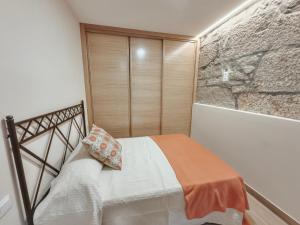 a bedroom with a bed and a stone wall at Apartamento Albar in Poio