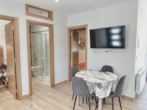 a dining room with a table and chairs and a television at Apartamento Albar in Poio