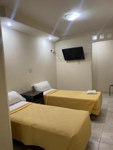 a room with two beds and a flat screen tv at San Remo City Hotel in Buenos Aires