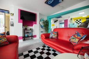 a living room with a red couch and a tv at Flawsome Stays Unique Home w Quirky basement for 12 Guests by Harbour and Town in Ramsgate