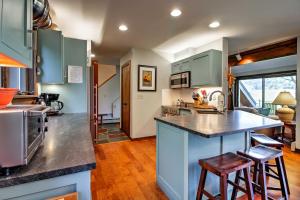 una cocina con armarios azules y una barra con taburetes en Stowe Vacation Rental with Deck and Mountain Views!, en Stowe