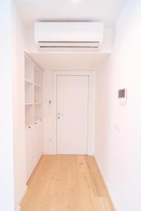 Cette chambre blanche dispose d'une porte et de parquet. dans l'établissement A Apartments, à Zadar