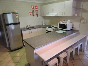 a kitchen with a counter with a microwave and a refrigerator at Main Beach Apartments in Byron Bay