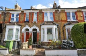 ein großes Backsteinhaus mit weißen Fenstern und einer roten Tür in der Unterkunft Peaceful London Retreat in London