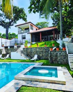 a villa with a swimming pool and a house at Habitaciones Casa Cuscatlan in Tamanique