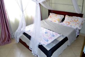 una camera con letto a baldacchino di olive Palm Suites a Njeru