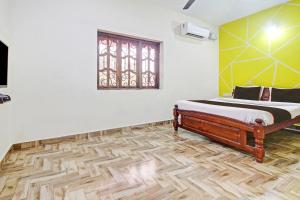 een slaapkamer met een bed, een raam en een houten vloer bij Ferns Guest House in Calangute