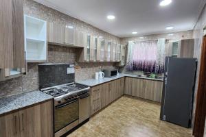 a kitchen with wooden cabinets and a stove top oven at Ace House in Nyeri