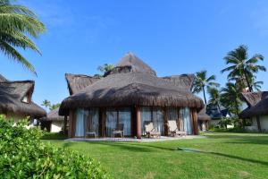 um resort com telhado de palha, cadeiras e palmeiras em Summerville Resort - All Inclusive em Porto de Galinhas