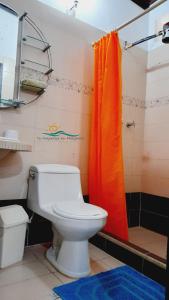 a bathroom with a toilet and an orange shower curtain at Casa Vacacional Lomas de Guayamury in Paraguachi