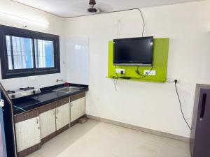 a bathroom with a tv on a wall with a sink at MANNAT VILLA 2bhk in Daman
