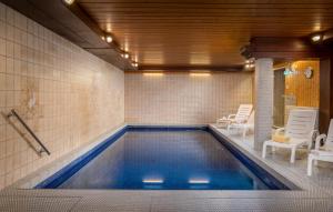 a swimming pool in a room with white chairs at Hotel Sonnenhof Teinachtal in Neuweiler