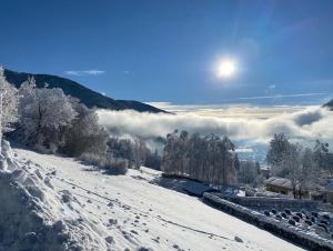 een besneeuwde heuvel met de zon in de lucht bij Haus Nocky Mountains in Radenthein