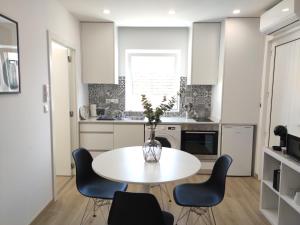 a kitchen with a table with chairs and a vase with flowers at Aveiro Ria House in Aveiro
