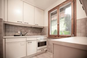 eine Küche mit weißen Schränken und einem Fenster in der Unterkunft Grubenmann Appartements - Flumserberg mit Bergpanorama in Flums