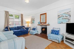 a living room with blue couches and a tv at Ruby Cottage - Beachside Cottage with Views in Saundersfoot