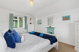a bedroom with a large white bed with blue pillows at Ruby Cottage - Beachside Cottage with Views in Saundersfoot