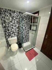 a bathroom with a toilet and a glass shower at Portal dos Anjos 03 in Arraial do Cabo