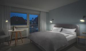 Schlafzimmer mit einem Bett, einem Fenster und einem Tisch in der Unterkunft Hotel Sonnenhof Teinachtal in Neuweiler