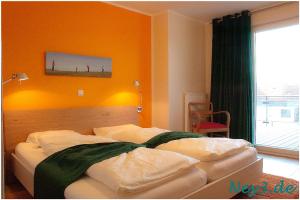 a bedroom with two beds with an orange wall at Ney3 in Norderney