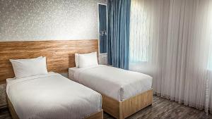 a hotel room with two beds and a window at Hotel Bankir Khiva in Khiva