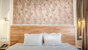 a bed with white pillows and a wooden headboard at Hotel Bankir Khiva in Khiva