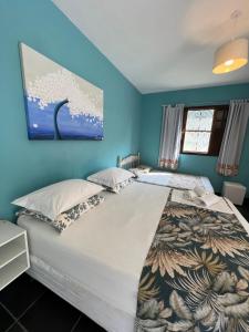 1 dormitorio con 1 cama grande y paredes azules en Suites Helena, en Ilhabela