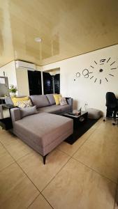 sala de estar con sofá y reloj en la pared en Senderos Apartment, Self Check- in, Airport SJO 5 MIN, en Santiago Este