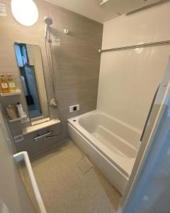 een badkamer met een wit bad en een douche bij 花田屋HANADAYA in Nishinotōindōri
