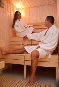 mężczyzna i kobieta siedzący w saunie w obiekcie Hotel Zlatni Bor w mieście Sokolac