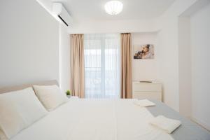 Un dormitorio blanco con una cama blanca y una ventana en Parkside Serenity: 1BR Ap near Parcul Politehnicii, en Bucarest