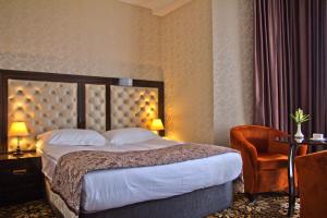 een hotelkamer met een bed en een stoel bij Discovery Hotel in Bisjkek