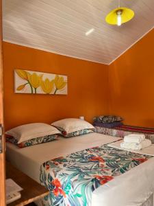 Duas camas num quarto com paredes cor de laranja em Suites Helena em Ilhabela