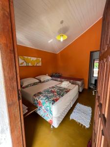 2 camas en una habitación con paredes de color naranja en Suites Helena, en Ilhabela