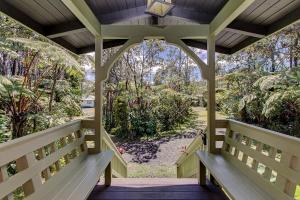 a porch with benches and a view of a yard at Halehikiola home in Volcano