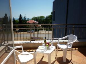 two chairs and a table with a bottle of wine on a balcony at Hotel Marant in Sozopol