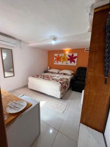 a bedroom with a bed and a couch in it at Suites Helena in Ilhabela