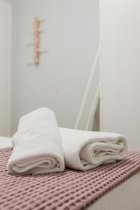 a stack of towels sitting on a bed at The Little Pigeon - Pink in Ioannina