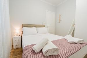 a white bedroom with a bed with towels on it at The Little Pigeon - Pink in Ioannina