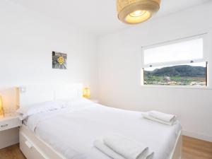 a white bedroom with a large bed and a window at Live Tata Casa con jardin y vistas in Las Lagunas
