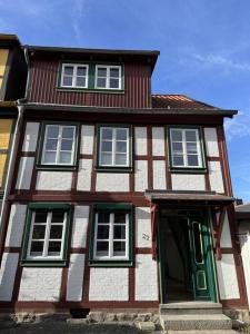 ein großes Holzhaus mit grünen und weißen Fenstern in der Unterkunft Ferienhaus im Altstadtzentrum in Wernigerode