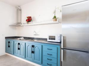 a kitchen with blue cabinets and a refrigerator at Live Tata Casa con jardin y vistas in Las Lagunas