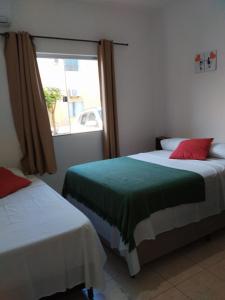 Duas camas num quarto com uma janela em Apto Aconchegante na Praia Coroa Vermelha em Santa Cruz Cabrália
