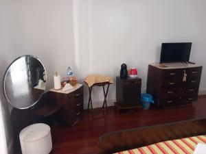 a bedroom with a dresser and a tv and a mirror at Casa do Brasão in Lajes do Pico