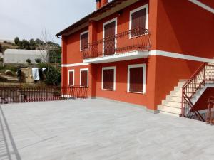un edificio rosso con un ampio patio di fronte di La Valle casa vacanze a Cascia