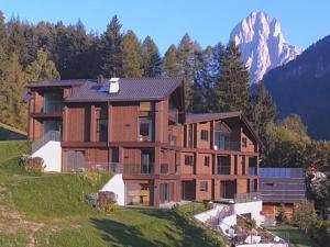 a house on a hill with a mountain in the background at Luxury Chalet P in Ortisei