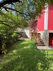 a house with a red wall and stairs next to a yard at Suites Helena in Ilhabela