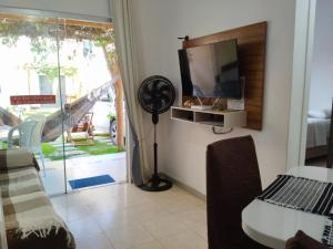 salon z telewizorem, stołem i krzesłami w obiekcie Apto Aconchegante na Praia Coroa Vermelha w mieście Santa Cruz Cabrália