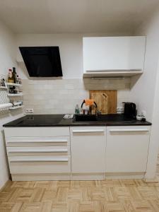 a kitchen with white cabinets and a black counter top at Traunsee Design Apartment for 2 People in Gmunden