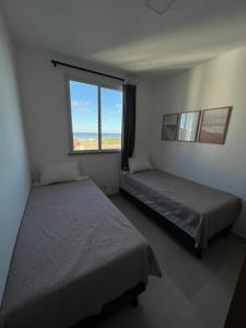 two beds in a room with a window at Vista mar no ultimo andar! in Ilhéus +27 photos